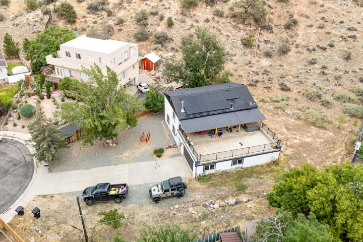 Expansive deck with black metal railings, covered patio area, and integrated solar panels on the roof