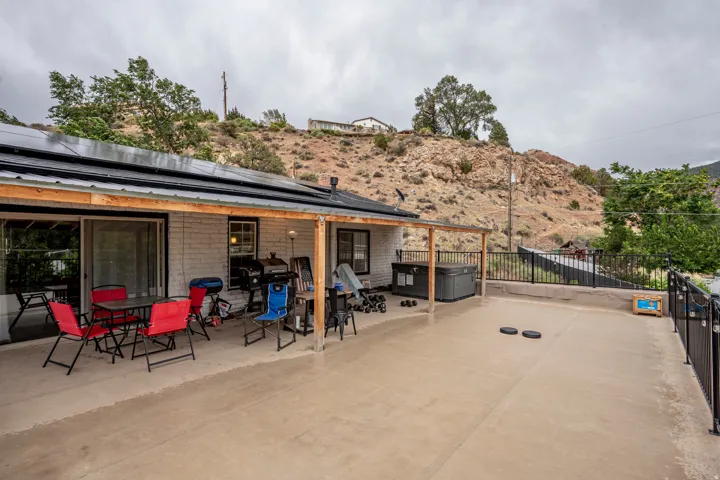 Expansive concrete patio with a covered section, bordered by a black metal railing