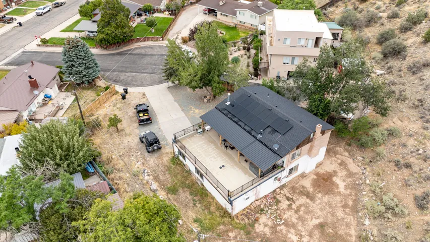 Expansive elevated deck with black metal railing, a shingled roof, a metal patio cover, and solar panels
