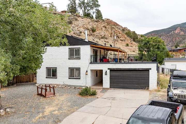 Two-story residence featuring a white brick exterior, an upper-level covered patio, and a dedicated garage space