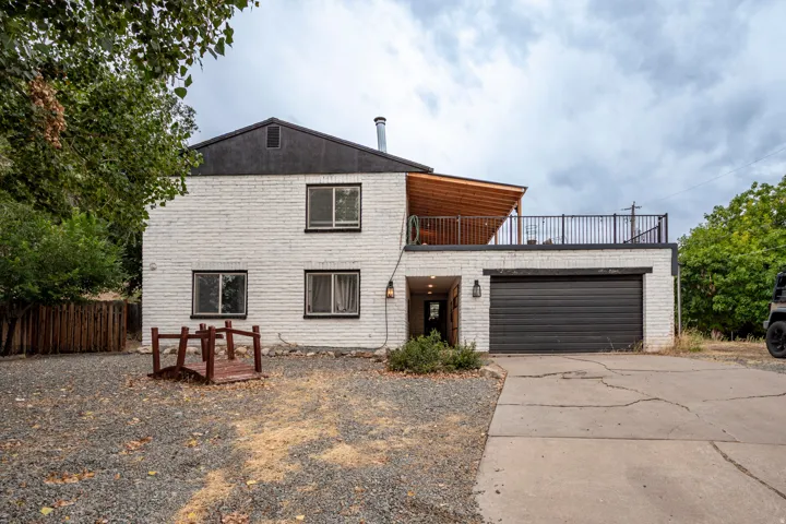 White brick exterior with a black garage door and upper-level deck