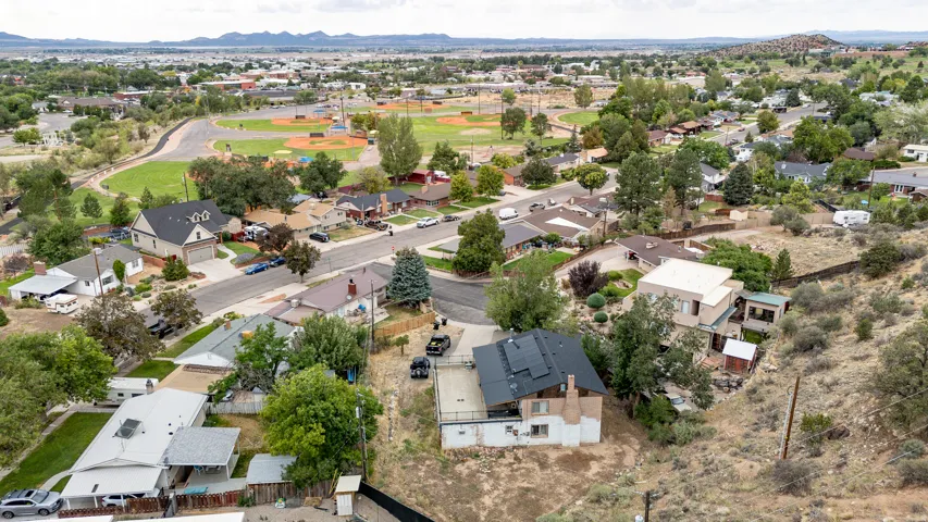 Residential neighborhood featuring established homes, mature trees, a paved street, and a sports field