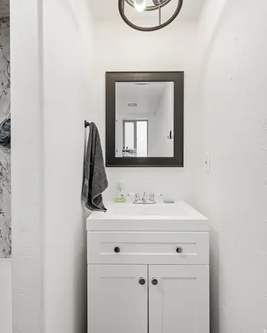 White vanity with integrated sink, chrome faucet, and dark-framed mirror