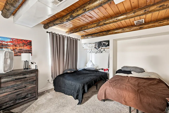 Exposed wood beam ceiling with wood paneling, recessed storage alcove, and neutral wall paint