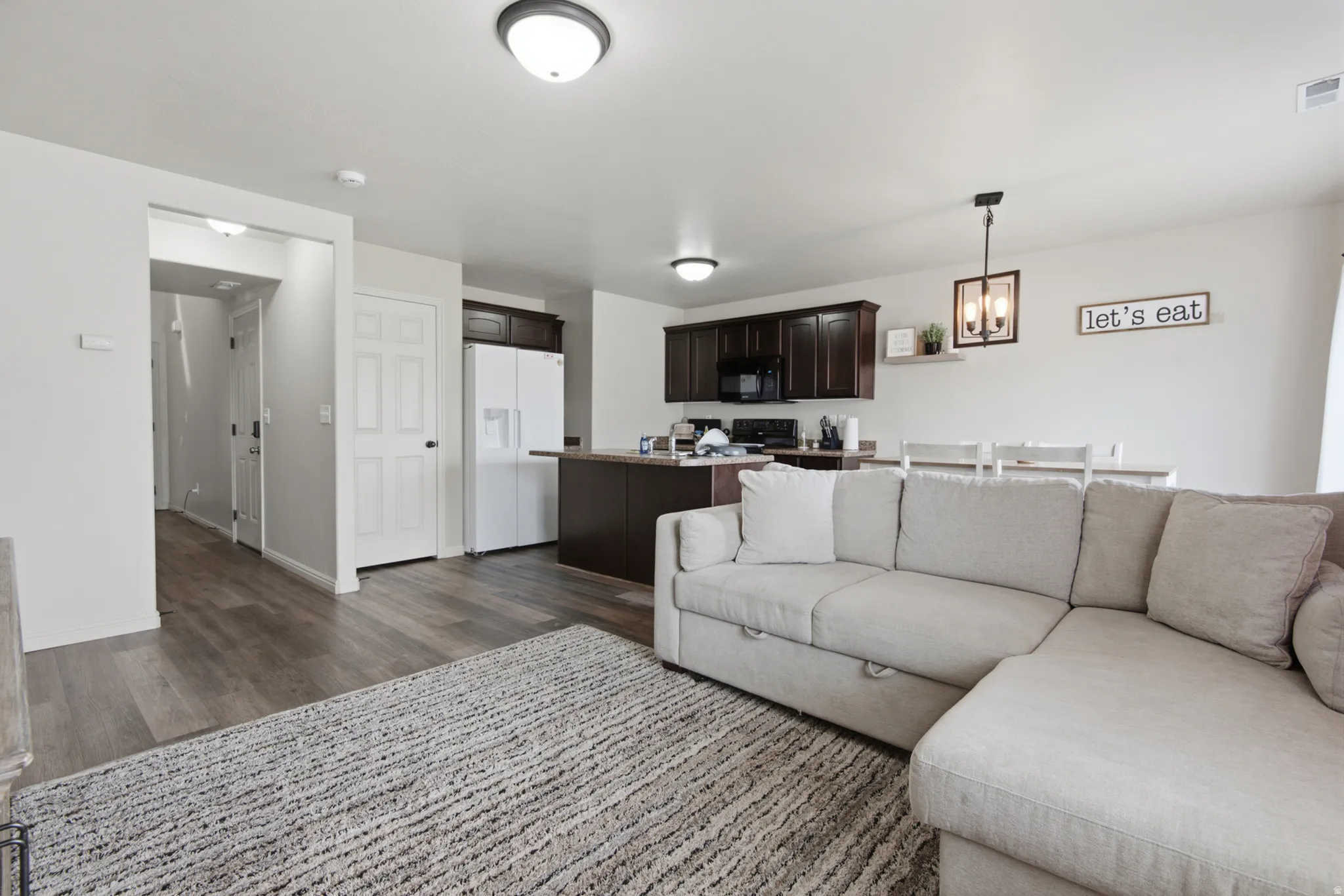 Open-concept living area with wood-finish flooring, recessed lighting, and dark wood cabinetry