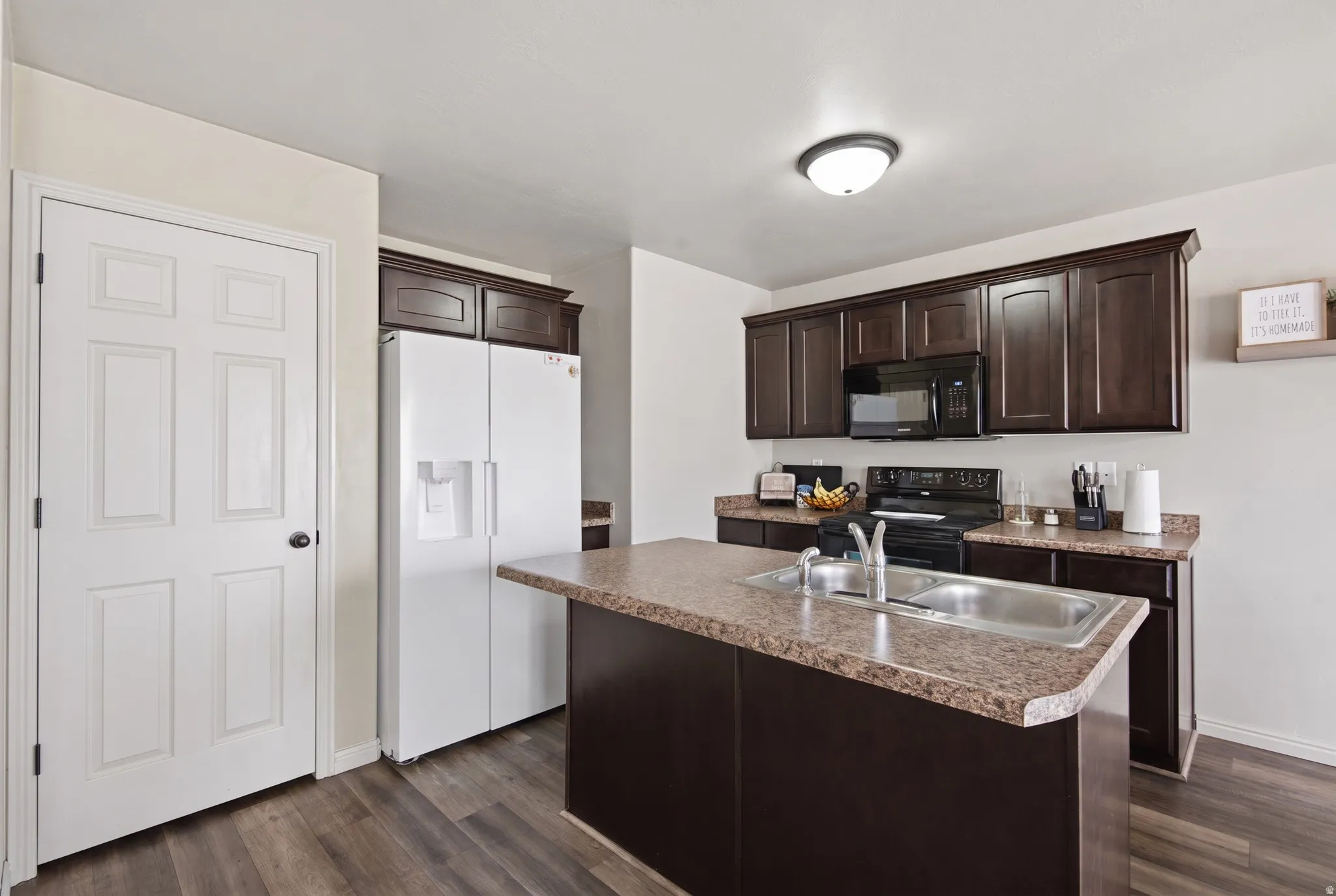 Kitchen featuring dark wood-finish cabinetry, solid surface countertops, and wood-finish flooring