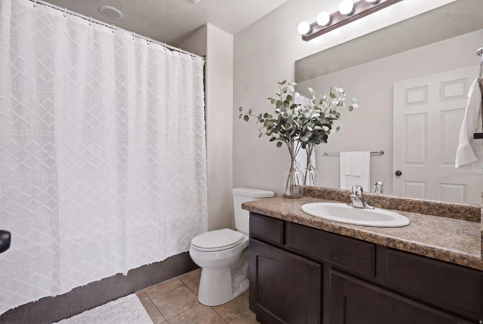 Single vanity with an integrated sink, dark wood-finish cabinetry, and a full-width mirror