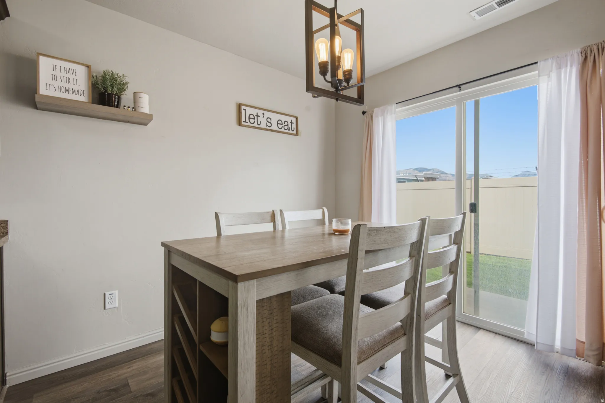 Sliding glass door, wood-finish flooring, recessed lighting, neutral wall paint, and a modern chandelier