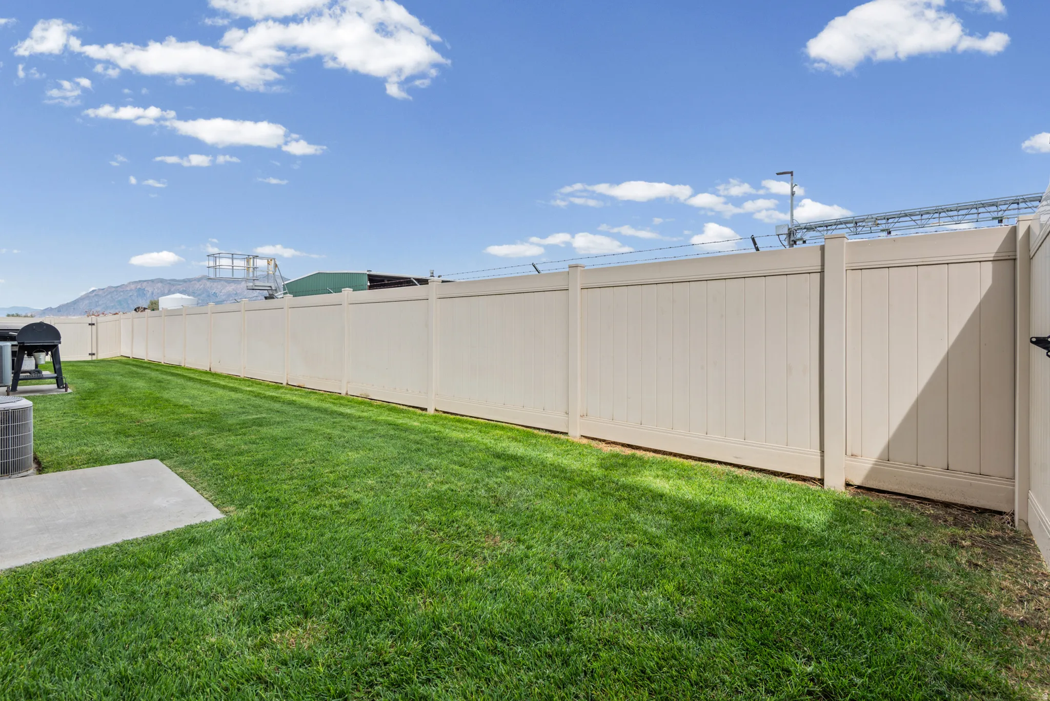 Expansive green lawn with a privacy fence and a concrete patio pad