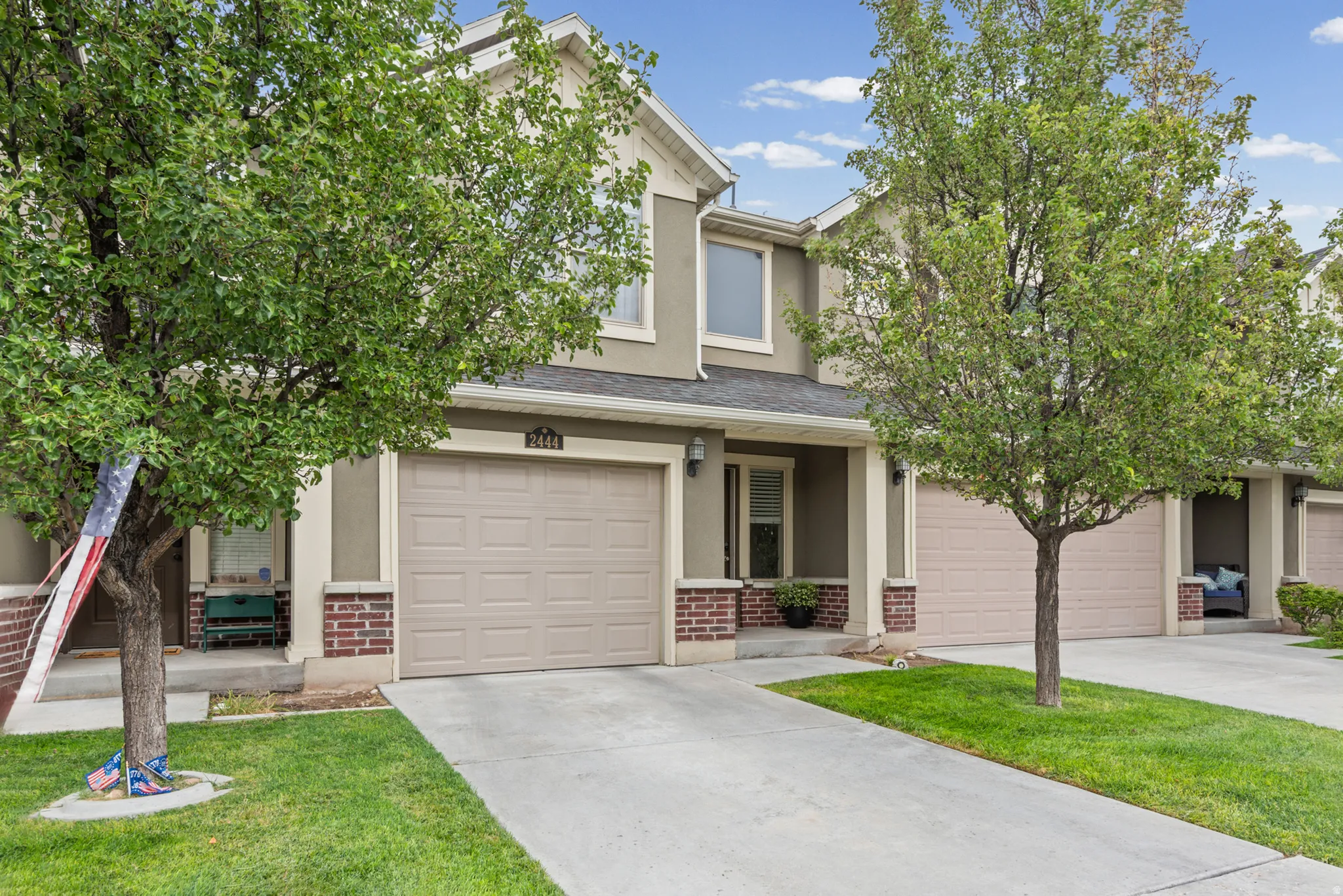 Stucco exterior with brick accents, attached garage, concrete driveway, and covered entry