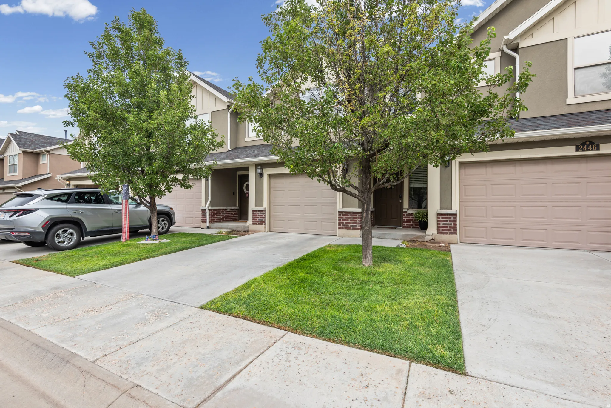 Tan stucco exterior with brick accents, attached garages, and concrete driveways