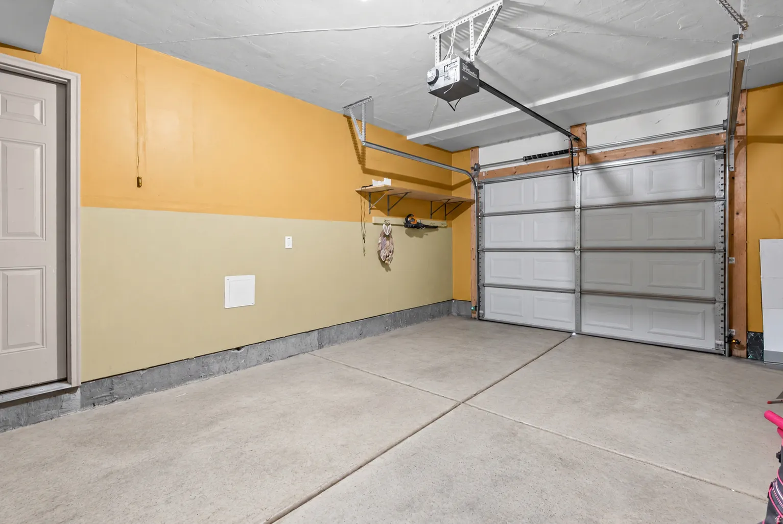 Concrete flooring with segmented design, two-tone painted walls, and a built-in storage shelf