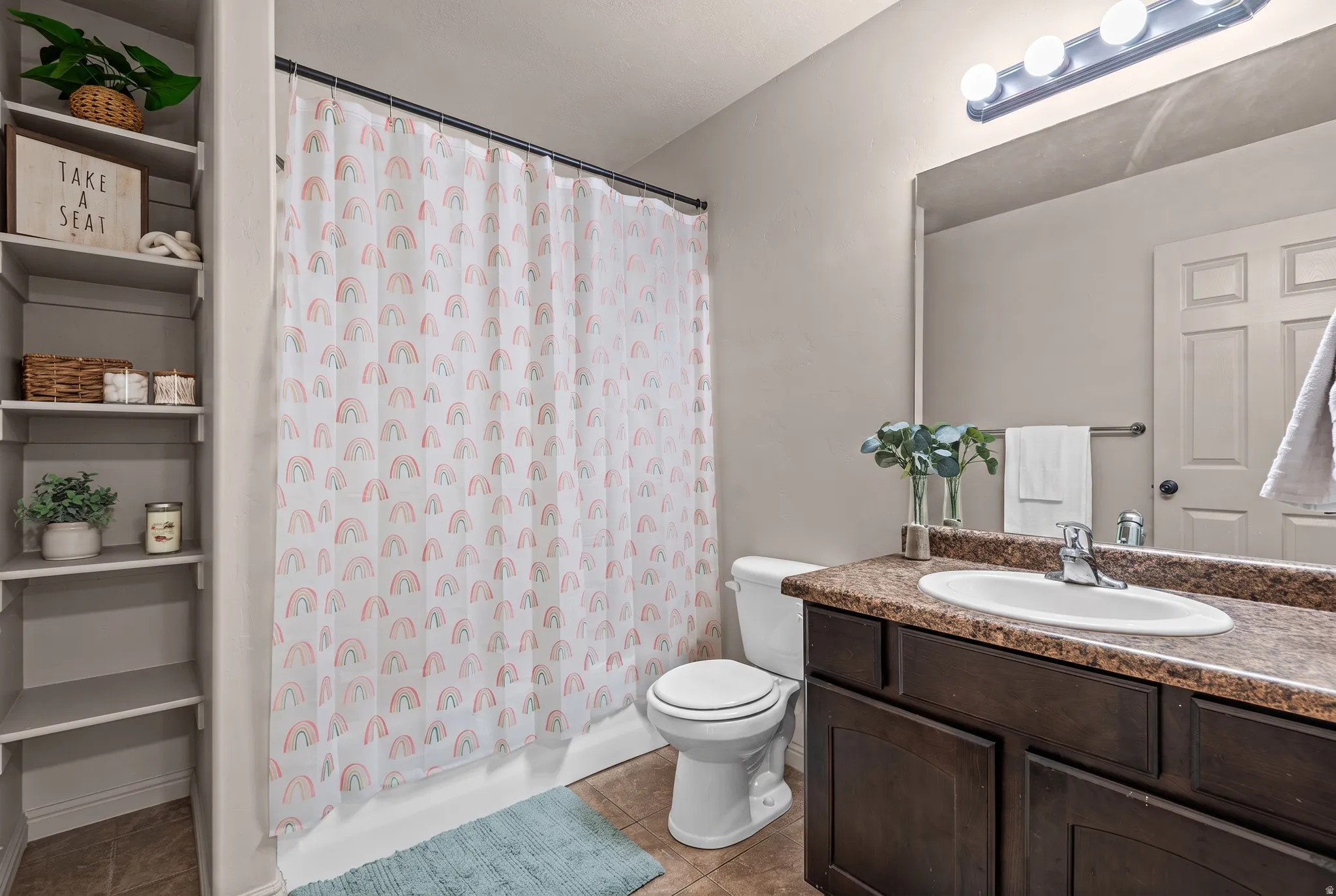 Bathroom featuring built-in shelving, a full bath with shower, a vanity with a surface-mounted sink, and an integrated mirror