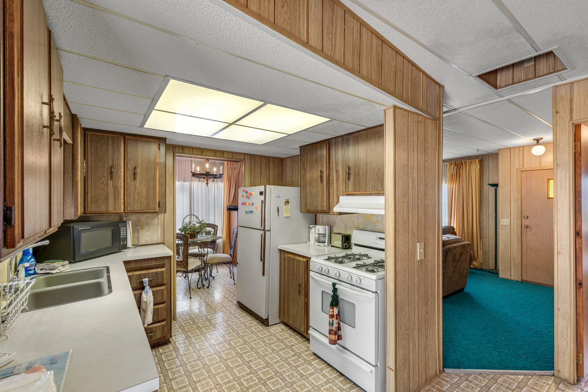 Kitchen with wood-finish cabinetry, a double basin stainless steel sink, and a four-burner gas range