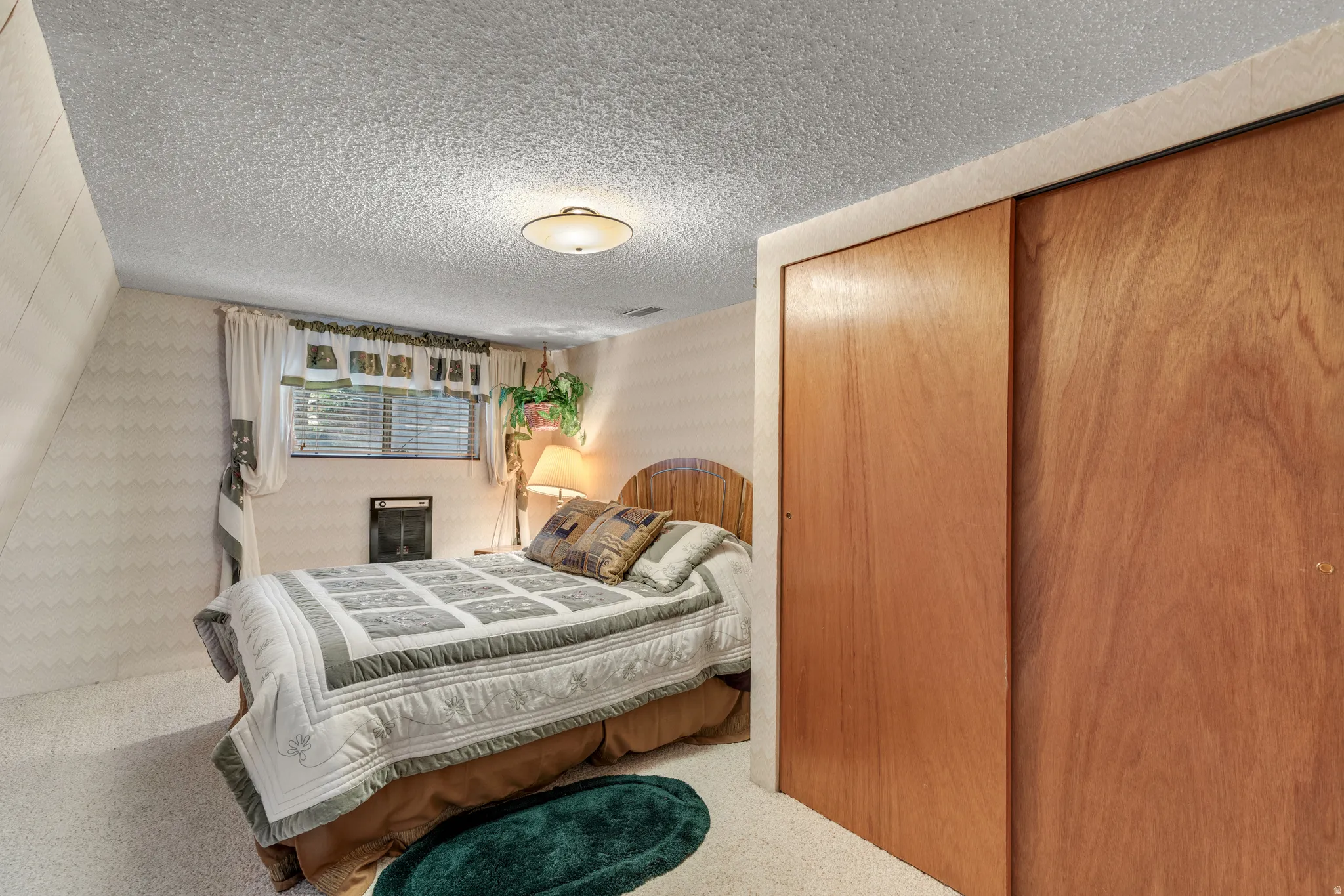 Sliding wood-finish closet doors, textured ceiling, and wall-mounted heating unit