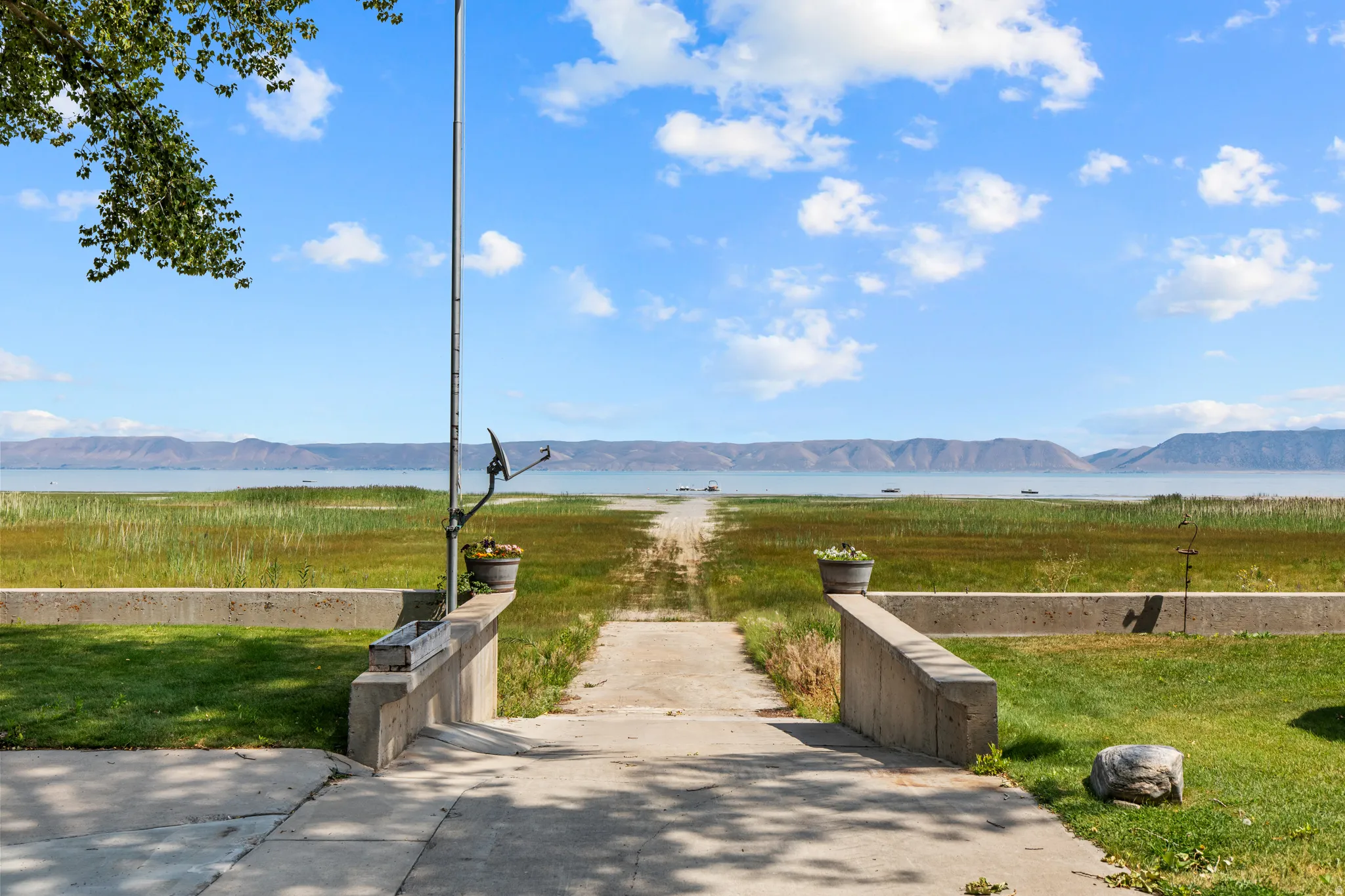 Expansive waterfront access with a concrete pathway and surrounding grassy areas