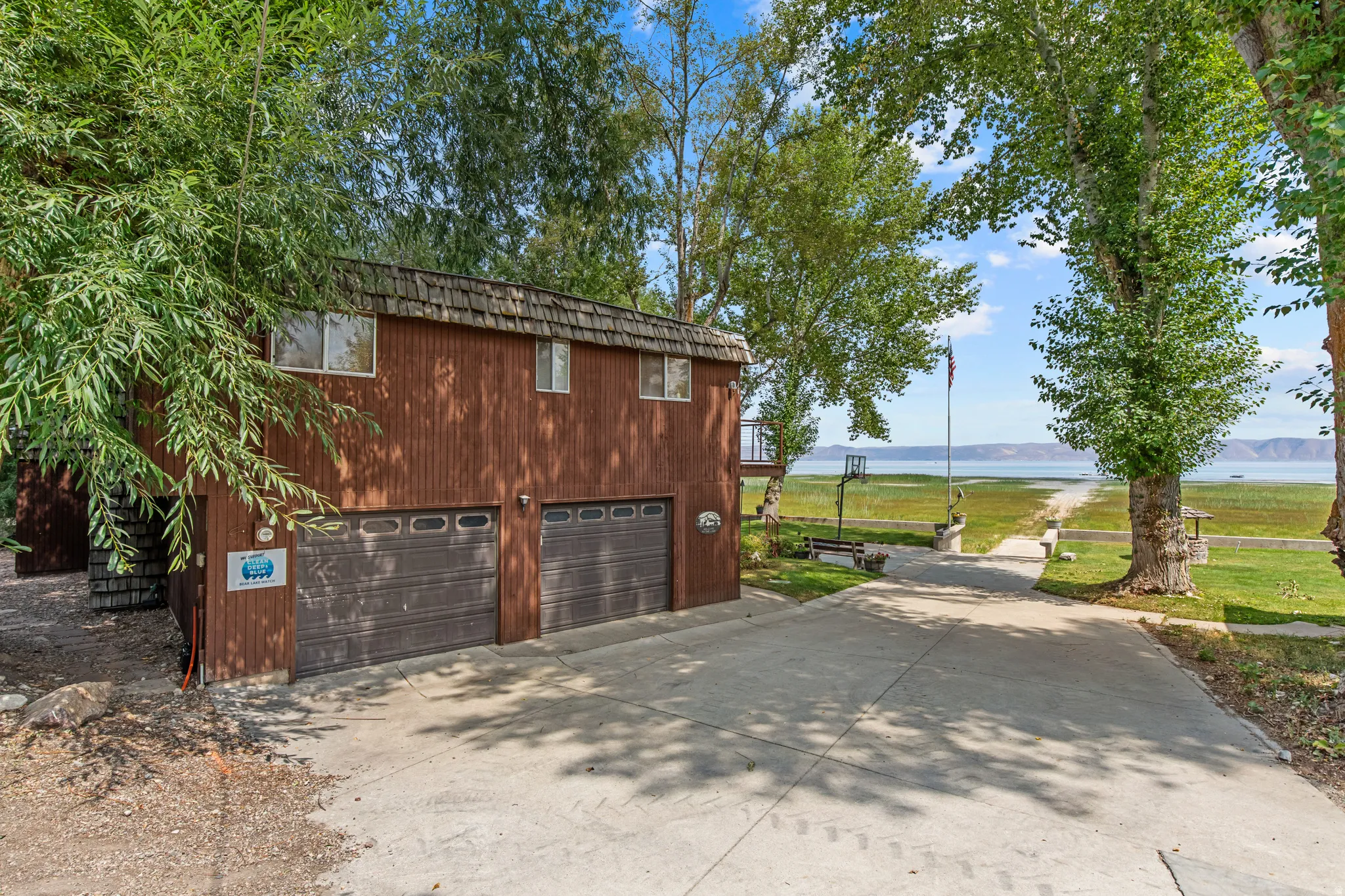 Wood-sided structure with a two-car garage, concrete driveway, and mature landscaping