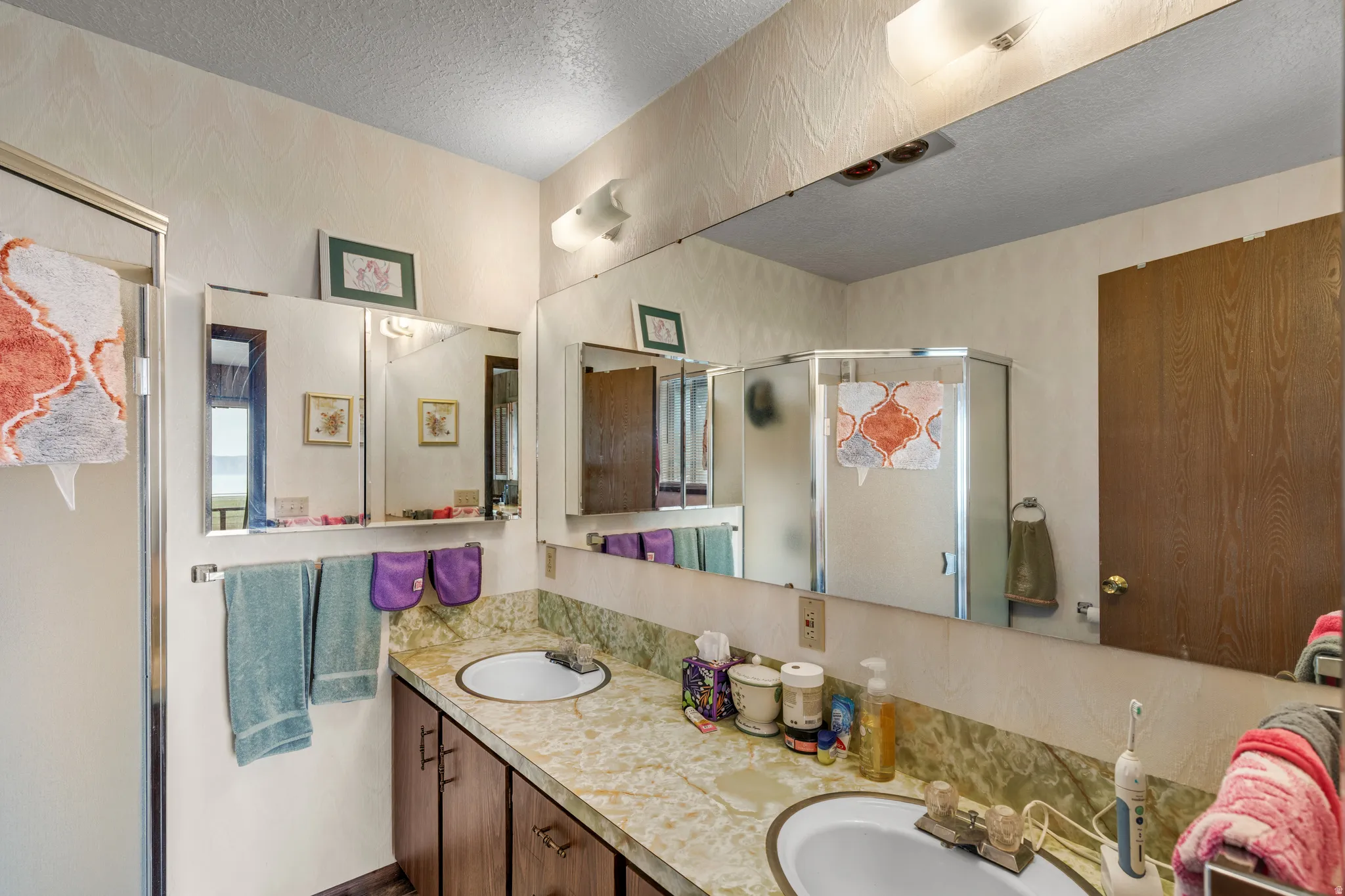Dual vanity with integrated sinks, framed mirrors, and a glass-enclosed shower