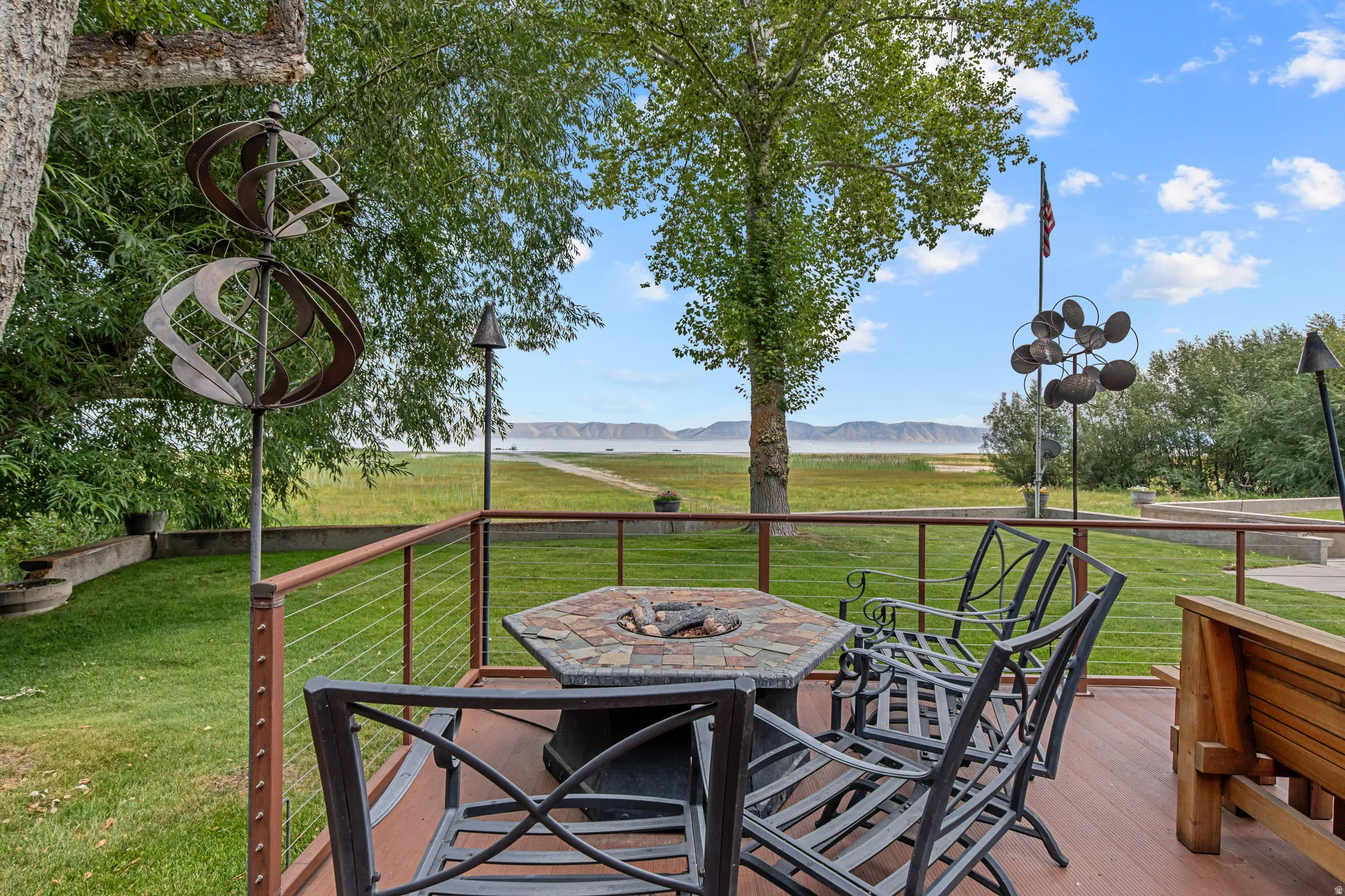 Expansive deck with cable railing, offering open-air seating and a fire pit