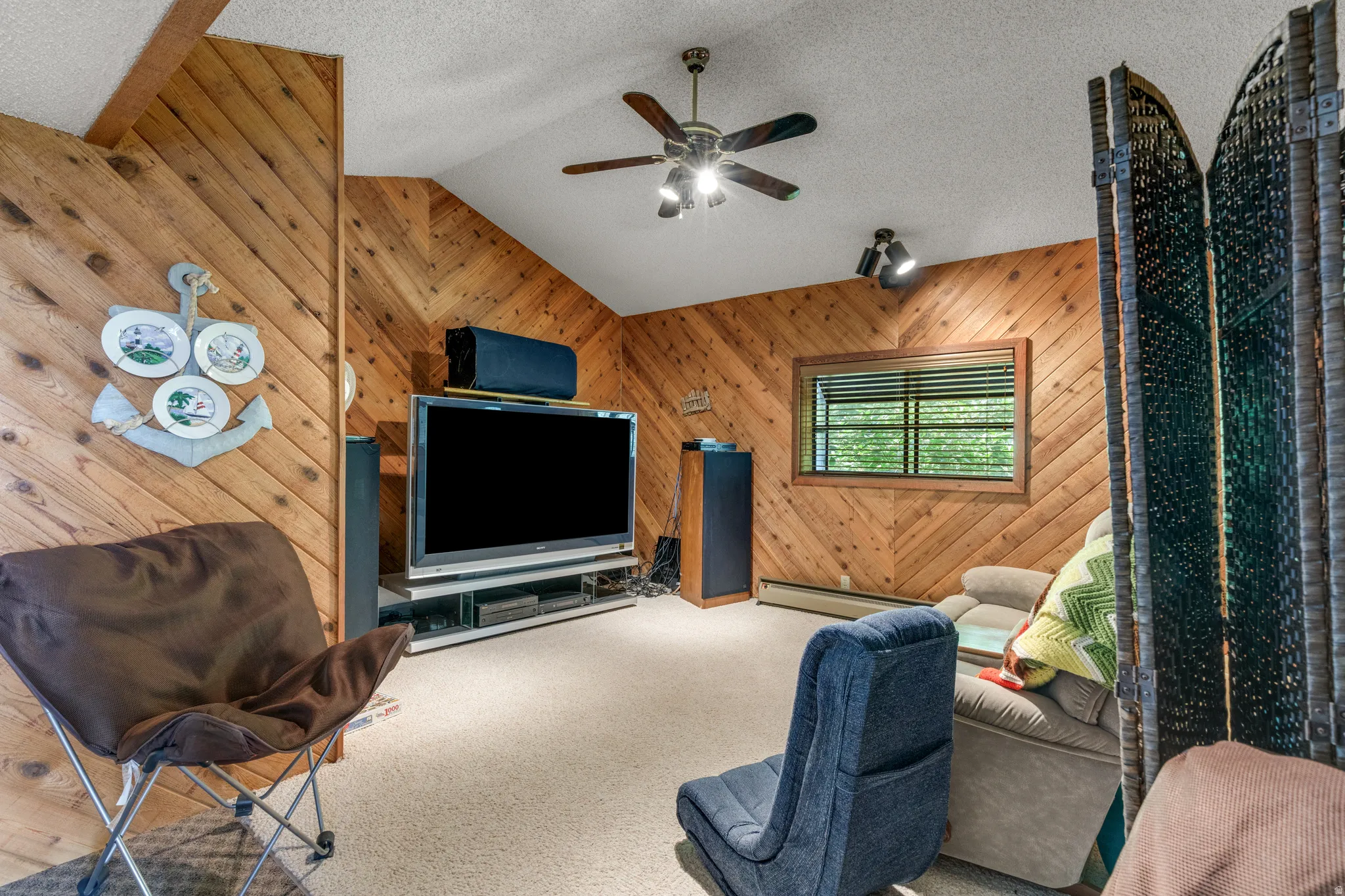 Sloped ceiling with recessed lighting, wood-paneled walls with a diagonal pattern, carpeted flooring, and a ceiling fan with integrated lighting