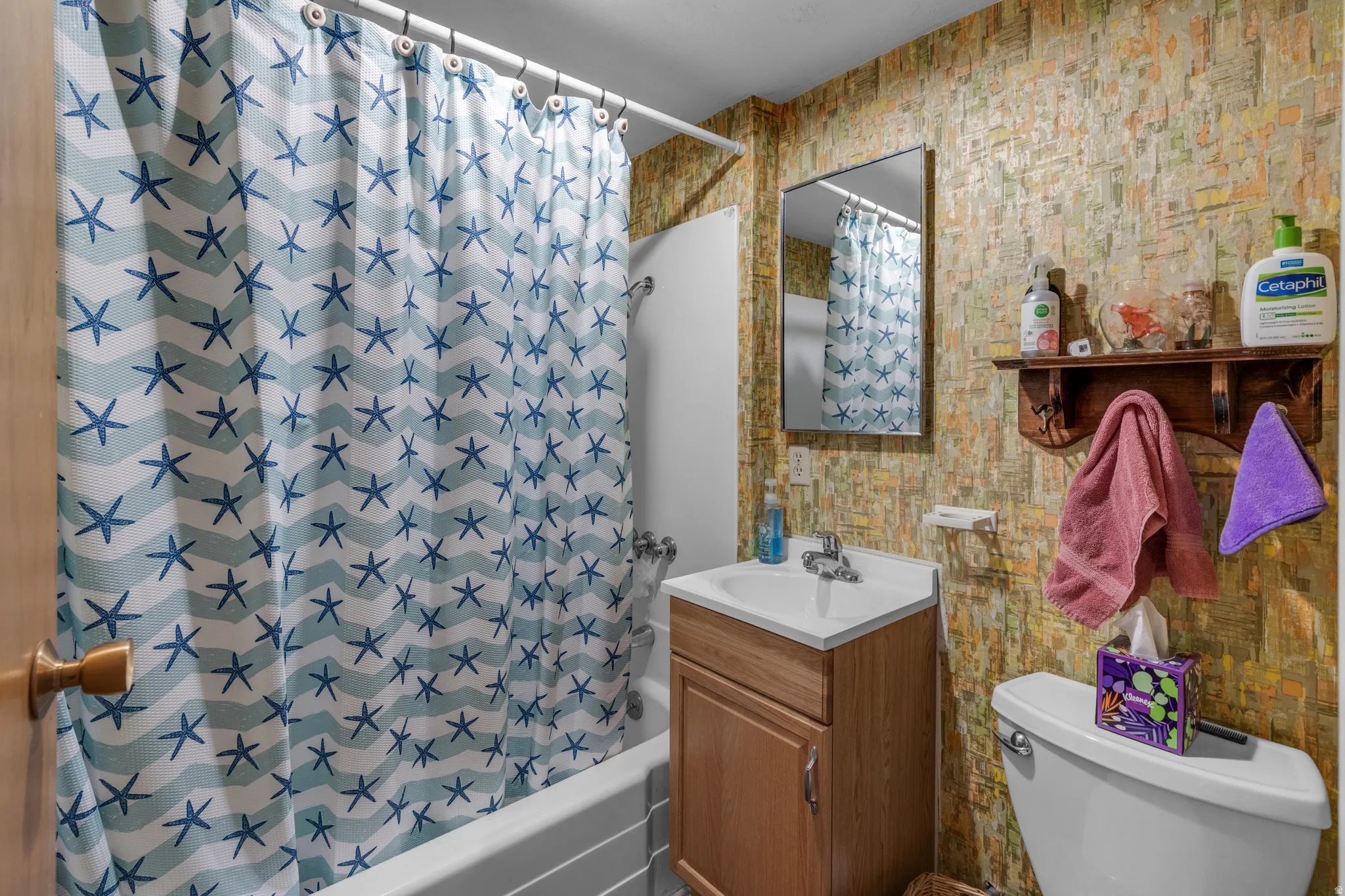 White bathtub with a shower, single vanity, and a wall-mounted mirror