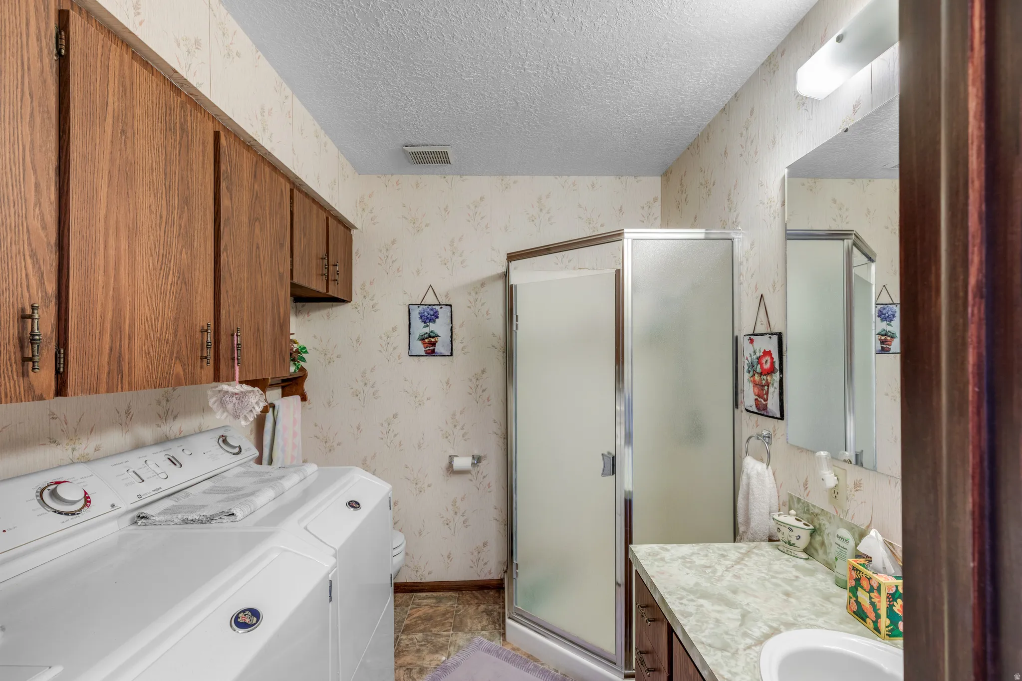 Full-height cabinetry, built-in vanity with integrated sink, and enclosed shower