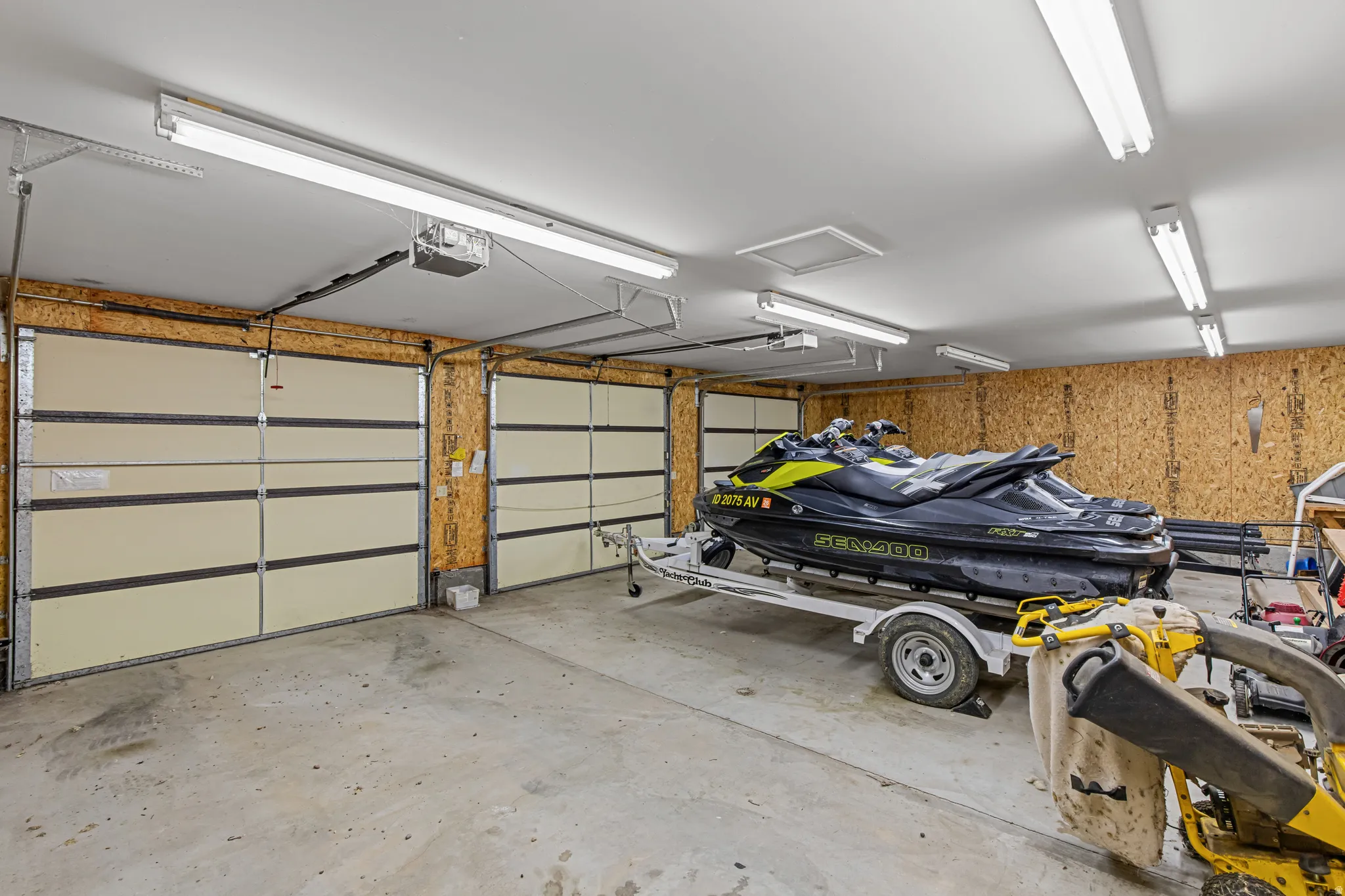Concrete flooring with multiple garage doors and exposed wood paneling