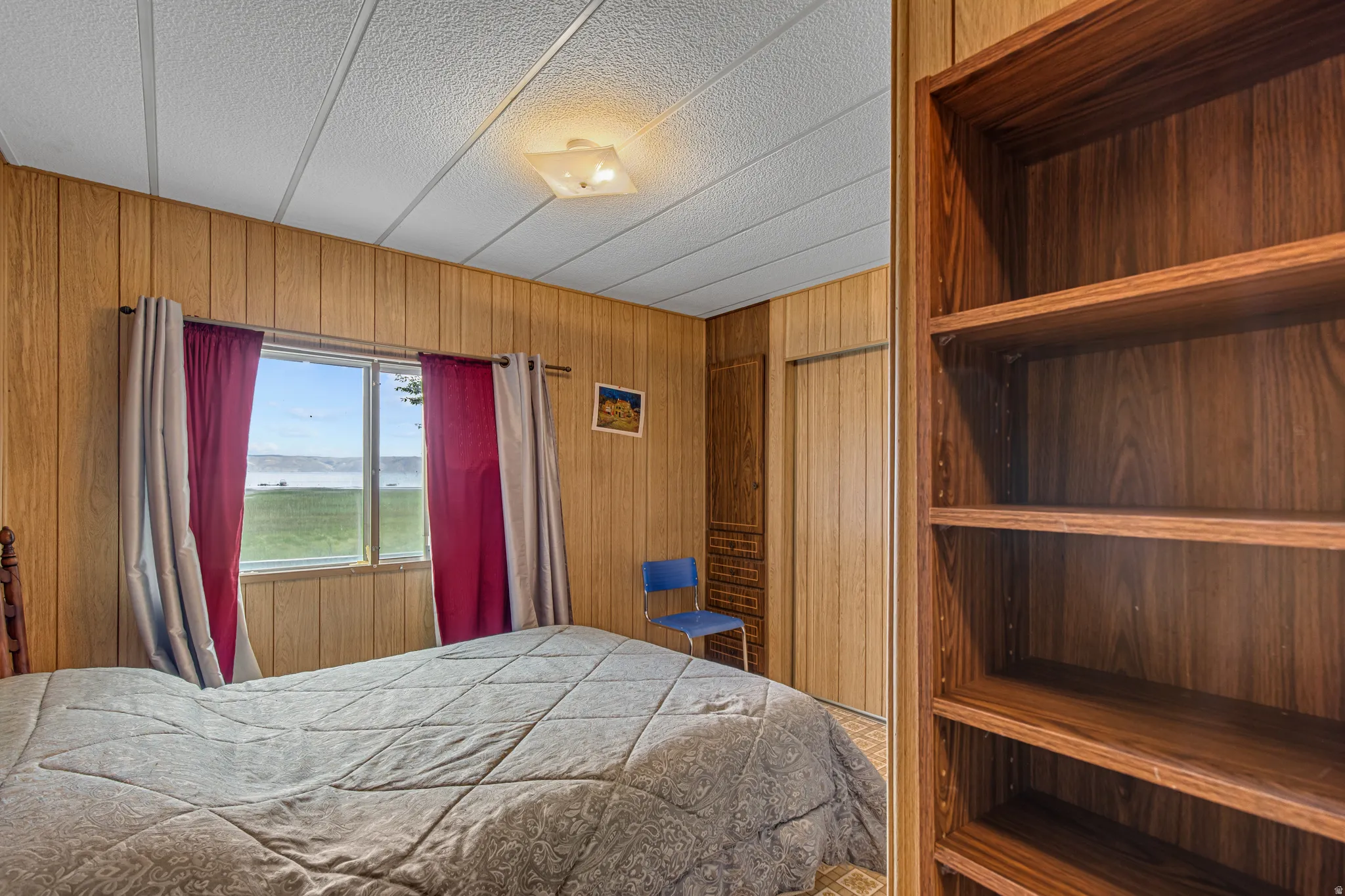 Wood-paneled walls and ceiling, built-in shelving, and a prominent window