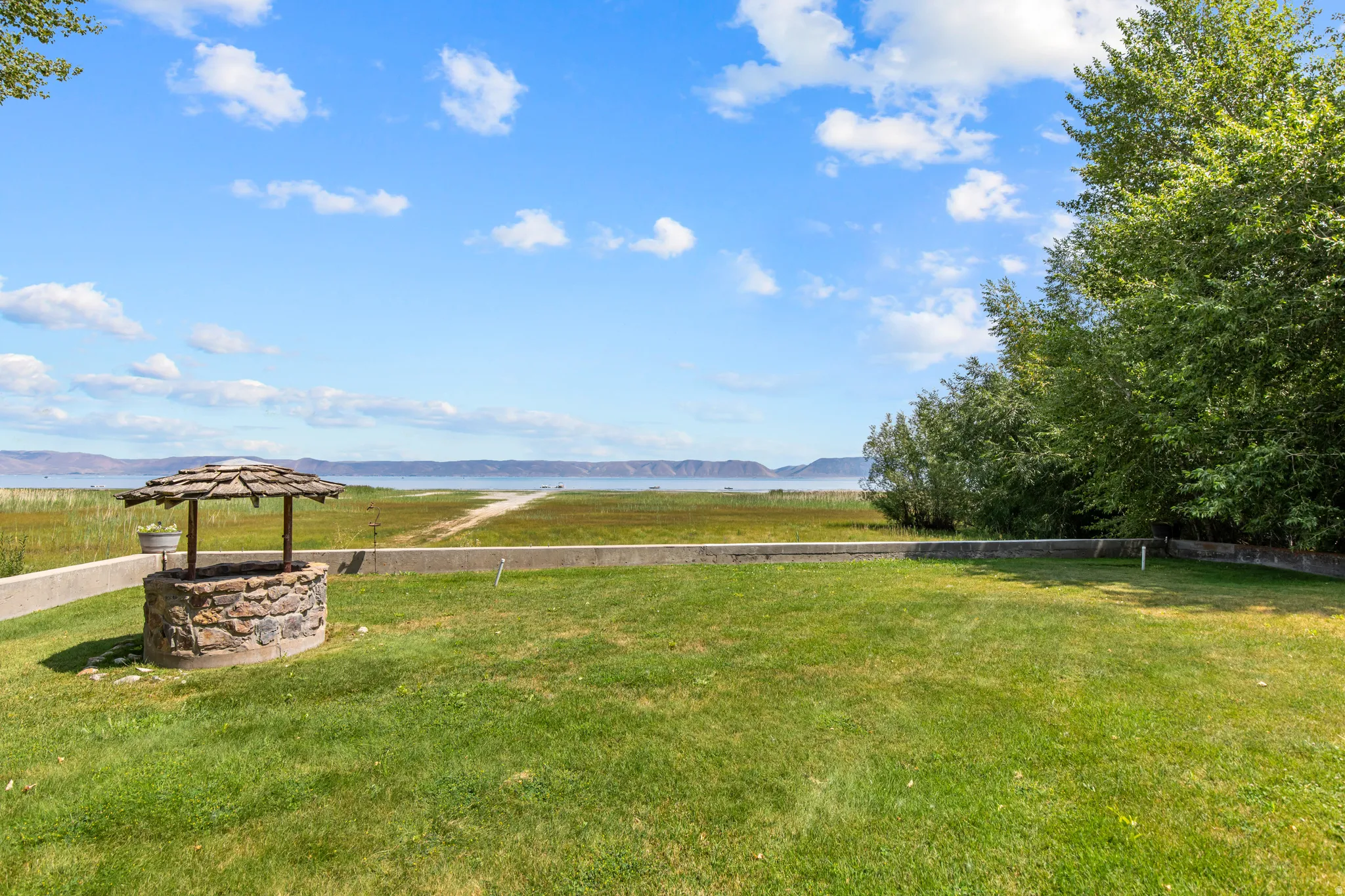 Manicured lawn with a stone well feature, bordered by a concrete retaining wall