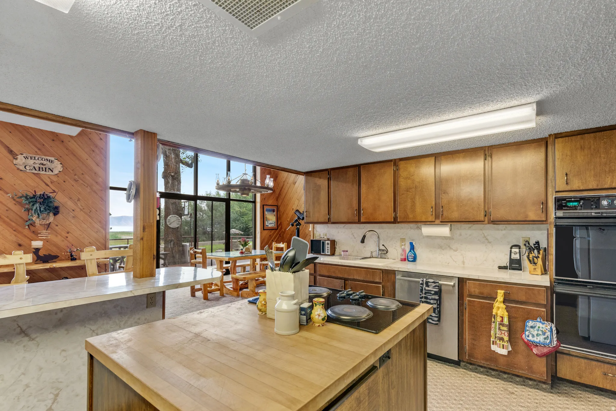 Kitchen featuring wood cabinetry, integrated double oven, and a center island with a cooktop