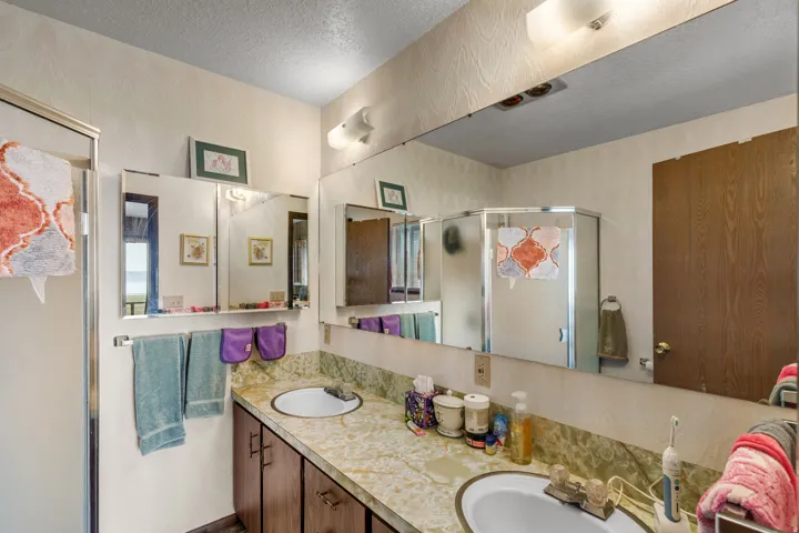 Dual vanity with integrated sinks, framed mirrors, and a glass-enclosed shower