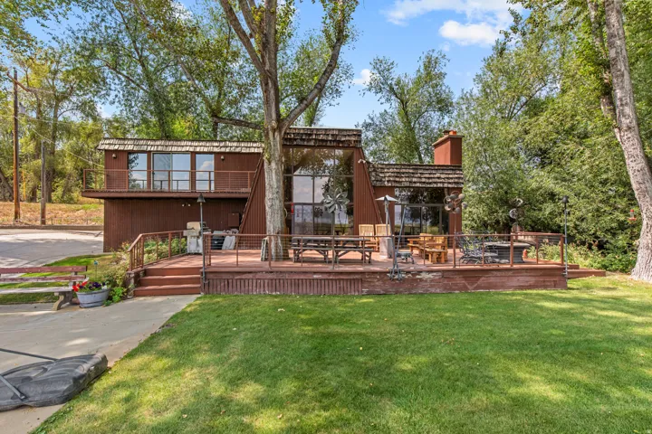 Multi-level exterior with a large wooden deck, expansive windows, and a prominent chimney