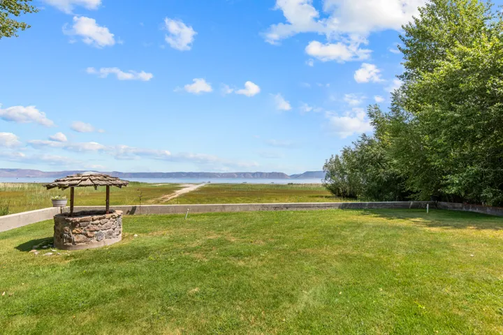 Manicured lawn with a stone well feature, bordered by a concrete retaining wall