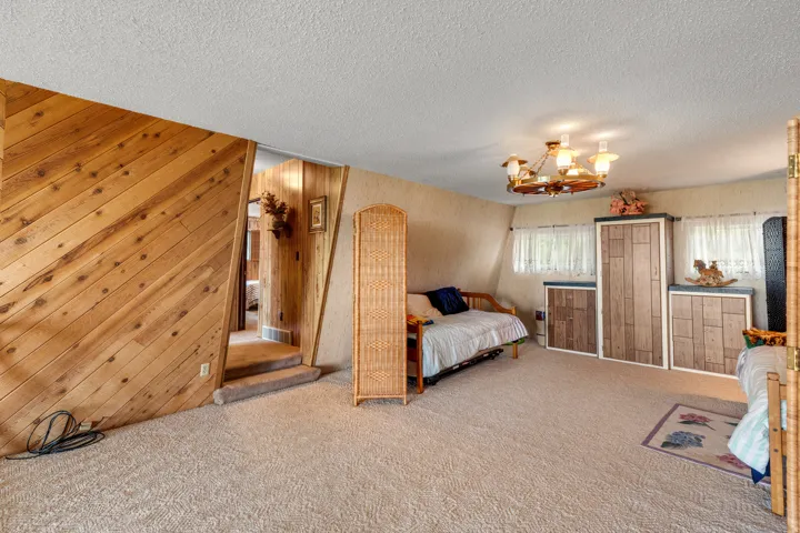 Angled wood paneling, sloped ceiling, built-in storage units, recessed windows, and a multi-arm chandelier