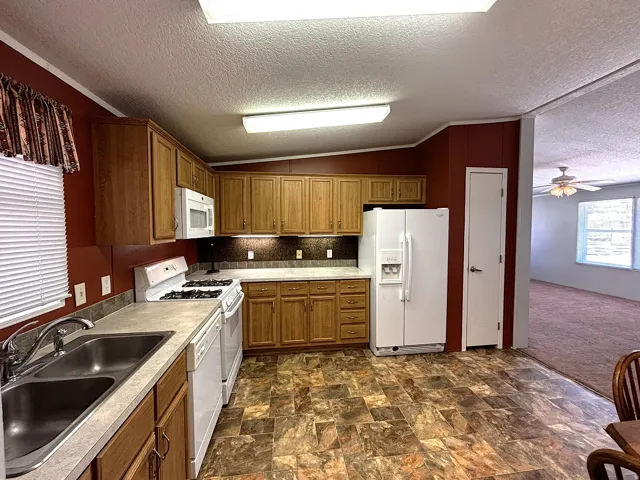 Kitchen featuring wood-finish cabinetry, laminate countertops, and a double basin stainless steel sink