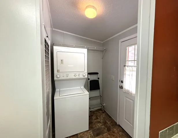 Laundry room, furnace, back door to patio. Stackable washer and dryer, ceiling-mounted light fixture, and a white paneled door with glass inserts