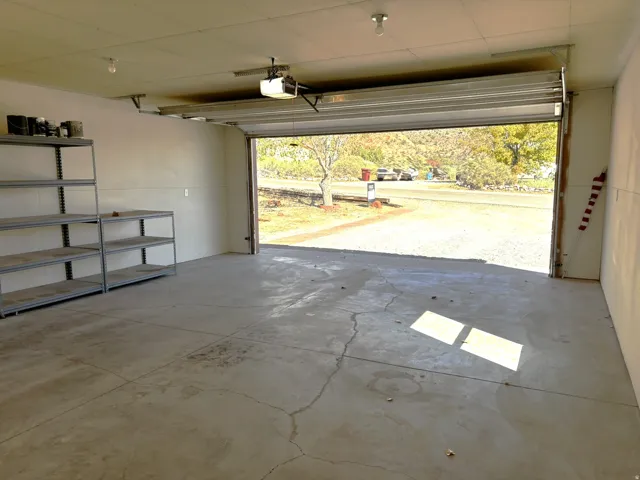 Attached garage with an overhead door, smooth concrete flooring, and painted walls