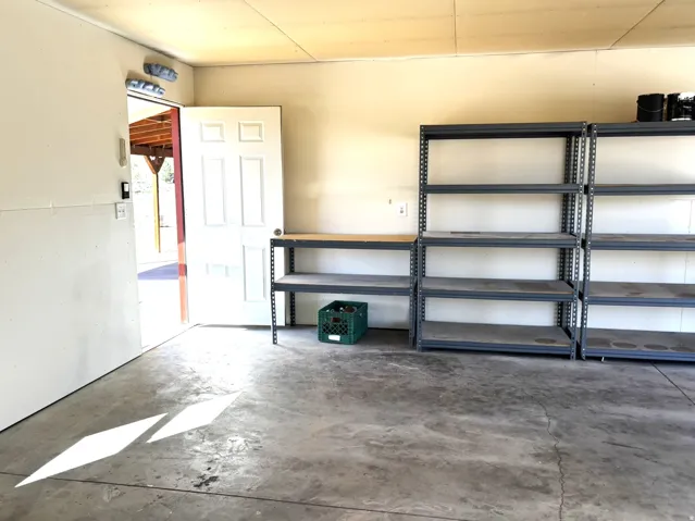 Concrete flooring, white paneled door, built-in metal shelving, overhead lighting