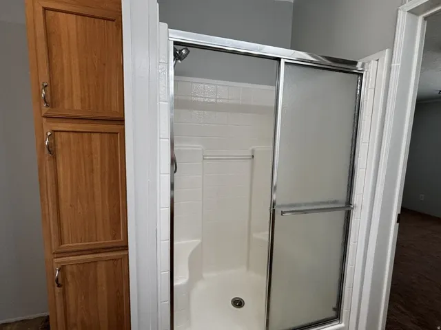 Walk-in shower with a chrome-framed glass enclosure, integrated seating, and a tiled surround