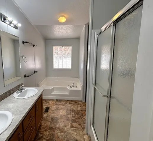 Primary suite bathroom .  Dual vanity with integral sinks, laminate countertop, and wood-finish cabinetry