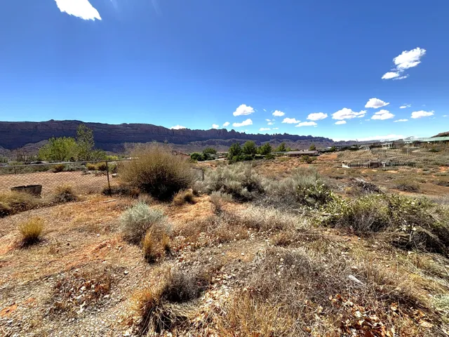Back lot. One acre. Expansive open terrain with natural brush and distant rock formations