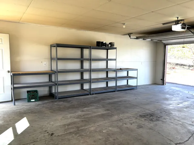 Spacious garage featuring a concrete floor, overhead lighting, and built-in shelving