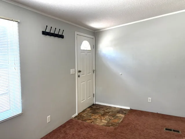 Entryway featuring a paneled door with an arched window, a wall-mounted coat rack, and brown-toned flooring