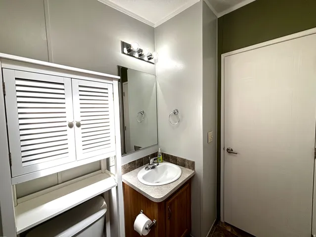 Wood-finish vanity with an integrated sink, polished chrome faucet, and coordinating wall-mounted light fixture