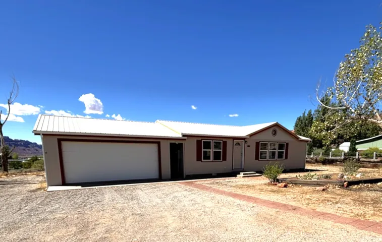 Single-story residence featuring a metal roof, attached garage, and red window shutters