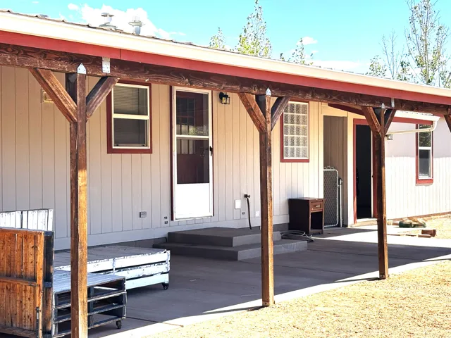 Expansive covered patio featuring exposed wood beams and posts, concrete flooring, and vertical panel siding