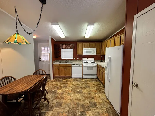 Kitchen featuring wood cabinetry, white appliances, and laminate flooring