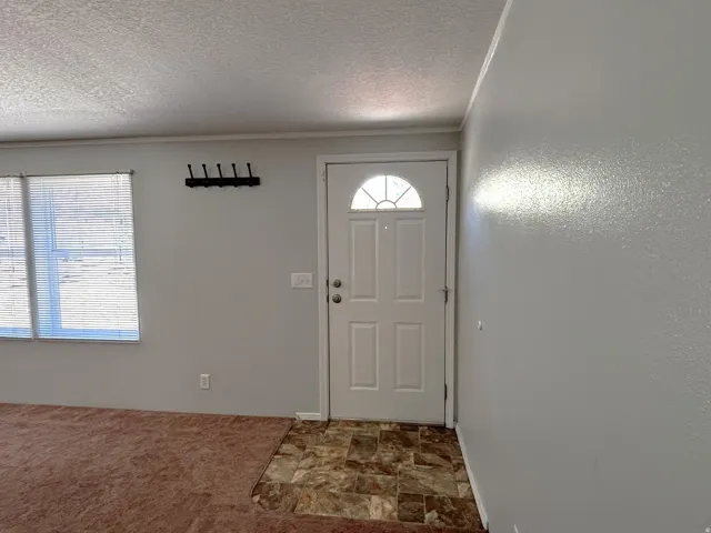 Entryway featuring a white paneled door with an arched glass insert, light gray walls, and a patterned tile floor