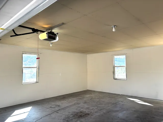 Attached garage with concrete flooring, two windows, and an automatic garage door opener