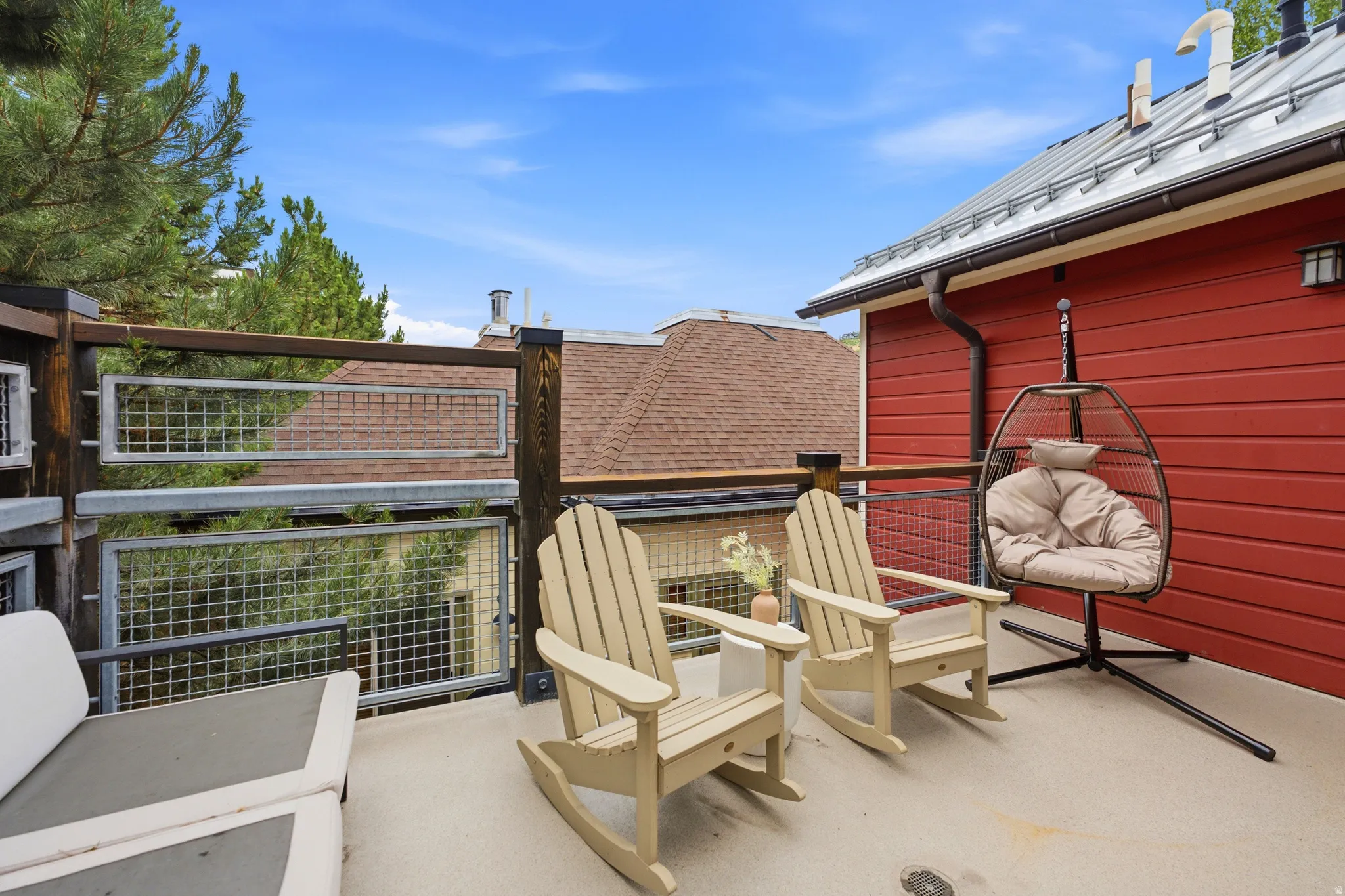 Spacious outdoor deck featuring a metal railing system, concrete flooring, and direct access to the red exterior siding